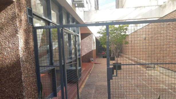 A gated courtyard with a brick wall, potted plants, and a metal gate. - BOULEVARD APARTMENT (Rosario)