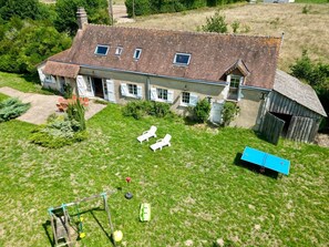 Una casa grande con un patio trasero amplio, que incluye un área de juegos y mobiliario de exterior.