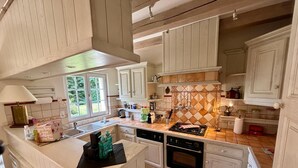 Une cuisine spacieuse avec des meubles blancs, un îlot central et une grande fenêtre qui laisse entrer la lumière naturelle.
