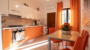Une cuisine moderne avec des meubles de rangement orange, une table à manger avec des chaises et une fenêtre avec des rideaux.