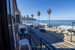 A balcony with a view of the sea, palm trees, and a street with cars. - Terrace by the Sea - Santa Maria di Castellabate (Santa Maria di Castellabate)