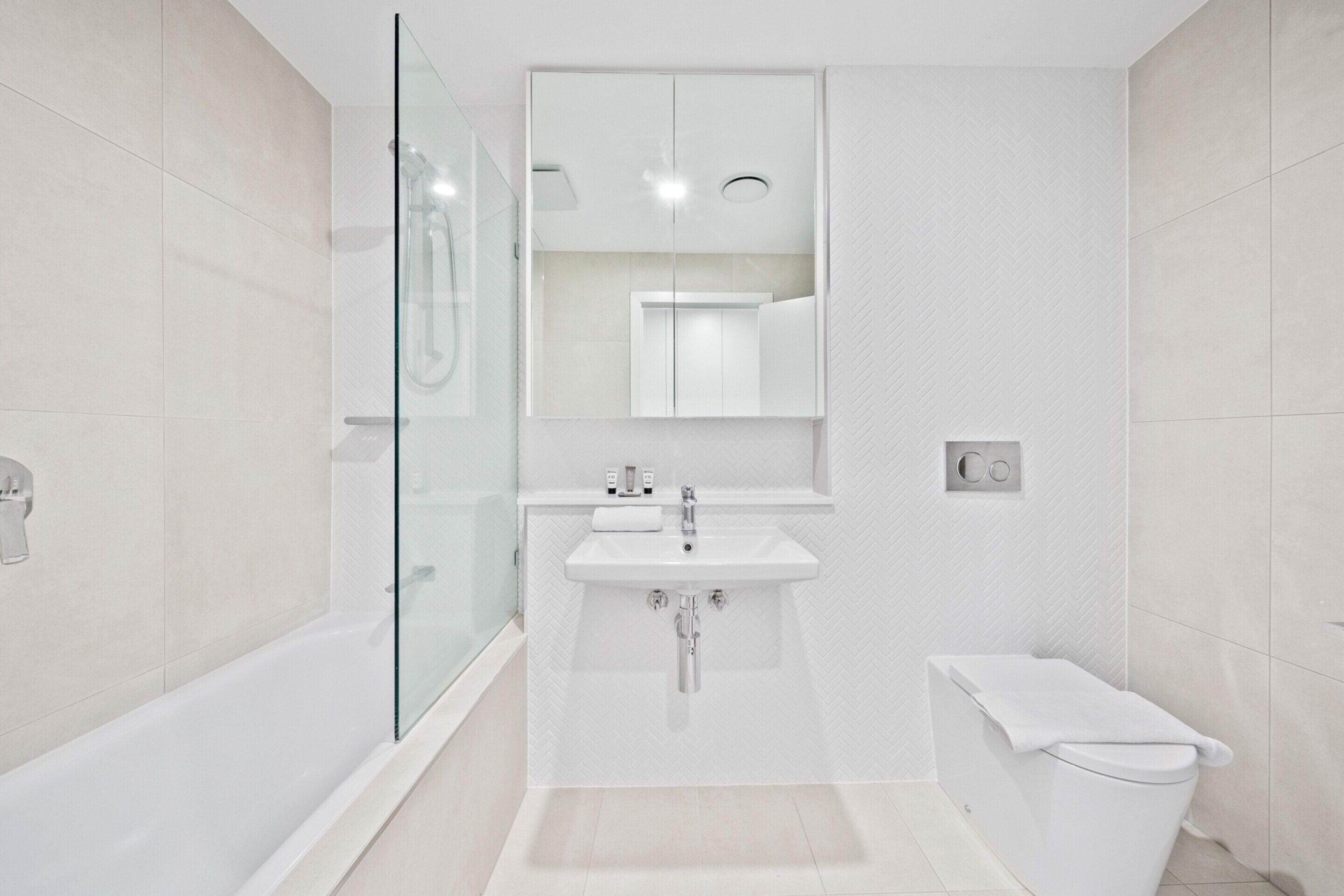 A modern bathroom with a glass-enclosed shower, a white sink, and a toilet.