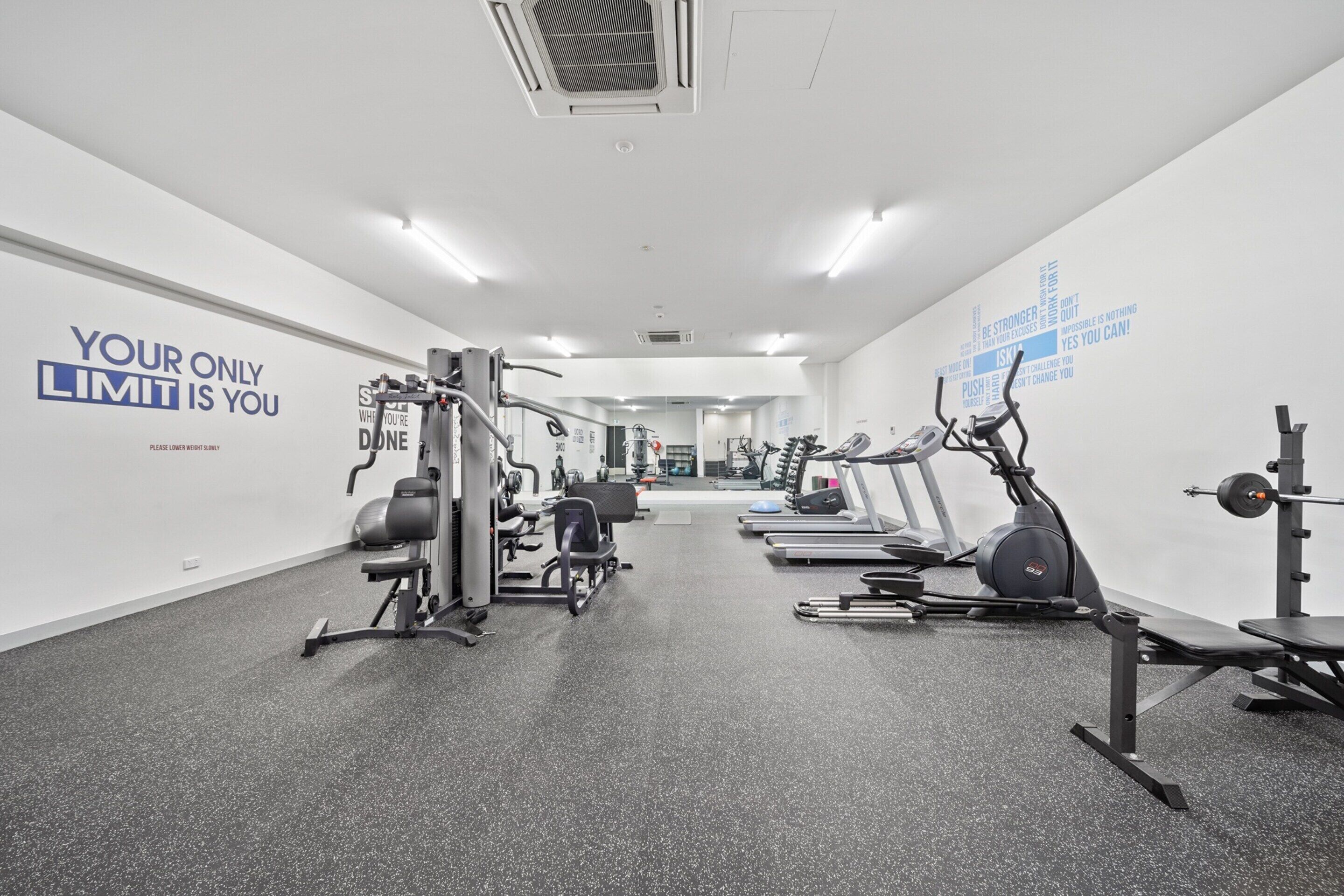 A gym with various exercise equipment, motivational wall art, and a clean, modern design.