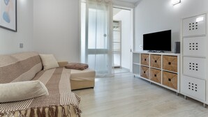 Een moderne woonkamer met een bank, televisie en opbergkasten.
