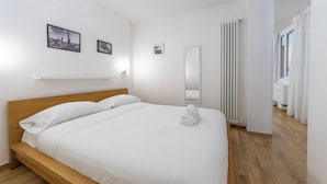 A neatly made bed with white linens, a wooden headboard, and a white wall with a framed picture. - HouSmart Val D'Aposa 5  (Bologna)