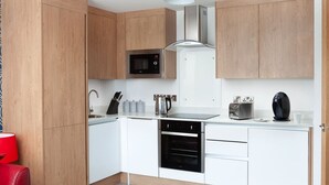 A modern kitchen with wooden cabinets, a microwave, a kettle, a toaster, and a coffee machine. - 2 Bedroom Marina Suite-203 (Kingston upon Hull)