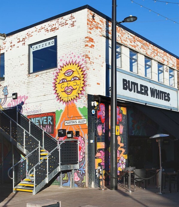 A building with a colorful mural, a staircase, and a sign for 'BUTLER WHITES'.
