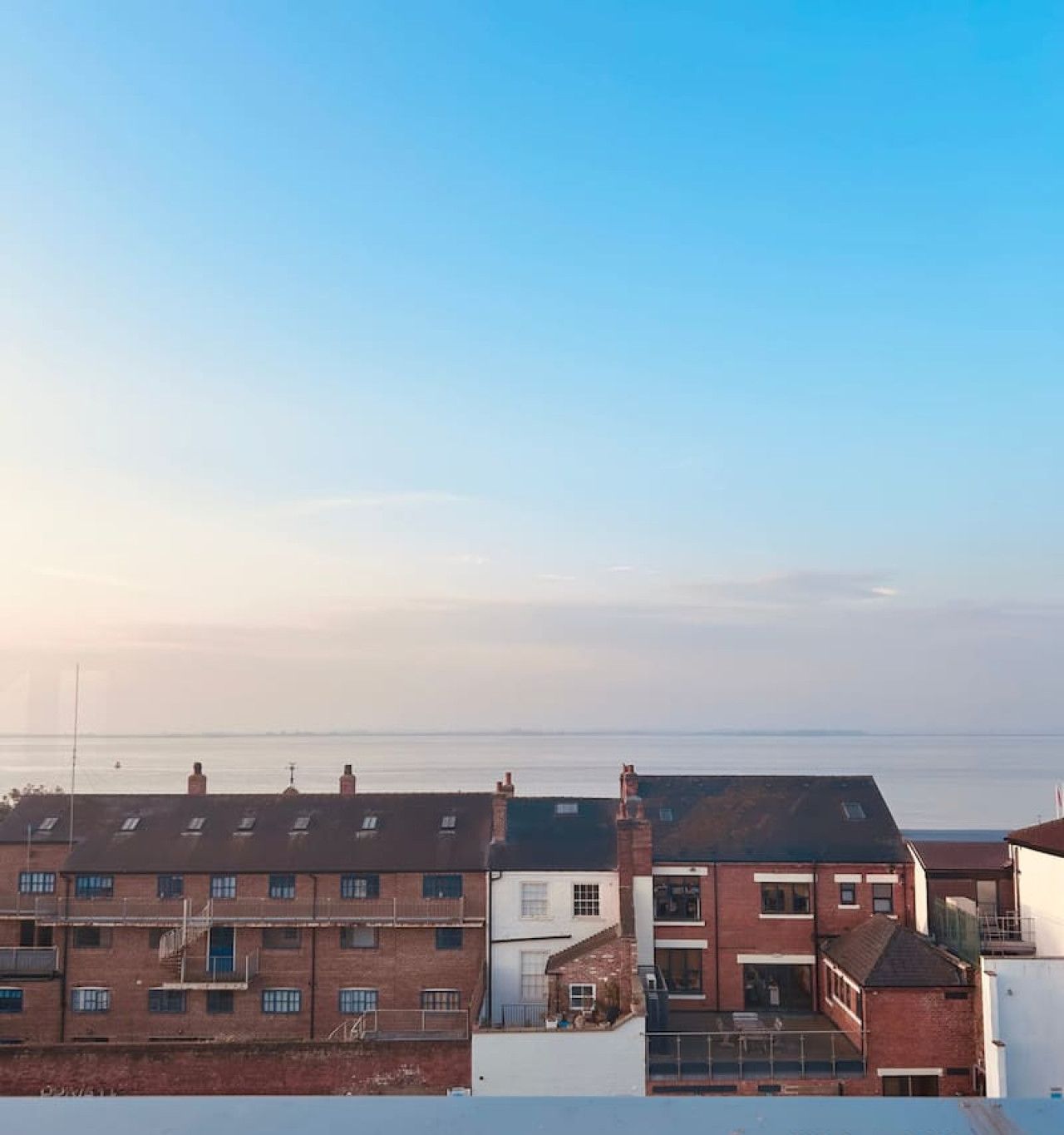 A row of terraced houses with a clear view of the sea in the background.