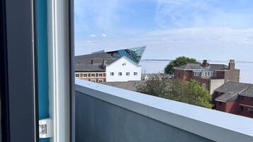 Uitzicht vanaf een balkon, heldere lucht, een gebouw met nummer 47 en een waterpartij op de achtergrond.
