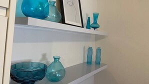 Una estantería con varios jarrones de vidrio azul y un cuadro enmarcado.