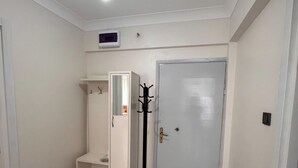 A room with a white wardrobe, a coat rack, a door, and a ceiling light. - Orçın Apartmanı (Lapseki)