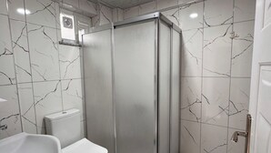 A bathroom with a shower enclosure, a sink, and a toilet. - Orçın Apartmanı (Lapseki)