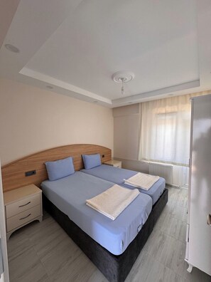 A double bed with a wooden headboard, a bedside table, and a nightstand. - Orçın Apartmanı (Lapseki)