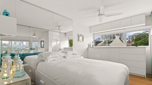 A modern bedroom with a large bed, a nightstand, a dresser, and a window with a city view. - Cosy 1-bed With Swimming Pool Facing Opera House (Sydney)