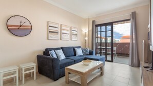 A living room with a sofa, coffee table, and a clock on the wall.