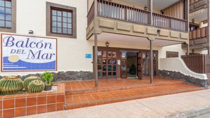 A building with a sign reading 'Balcon del Mar,' a tiled entrance, and a small garden with cacti.