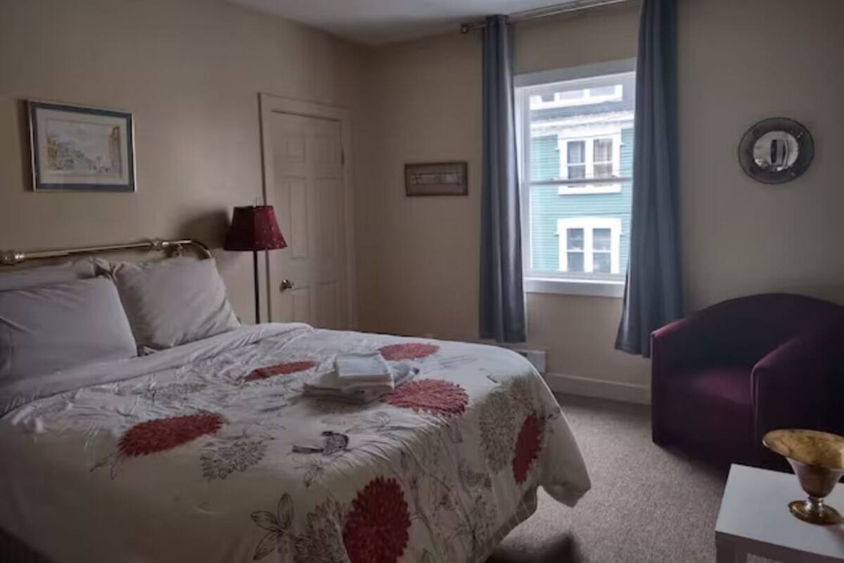Une chambre à coucher avec un lit, une chaise, une fenêtre et une porte.