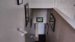 Una escalera con barandilla, peldaños alfombrados y una puerta al final.