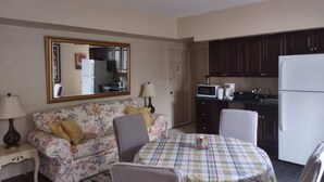 Un espacio habitable compacto con kitchenette, un sofá, una mesa de comedor y un espejo.