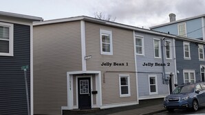 Una hilera de casas adosadas con letreros que dicen "Jelly Bean 1" y "Jelly Bean 2", un cartel de calle que indica "Fenner's Lane" y un coche estacionado.