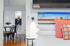 Una camera da letto moderna con un letto, cuscini, un quadro e una libreria.