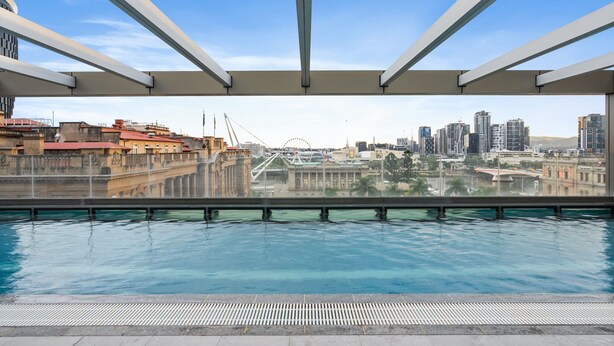 Une piscine sur le toit offrant une vue sur la ville, notamment sur un pont et des immeubles de grande hauteur.
