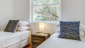 A bedroom with two beds, a nightstand with a lamp, and a window with a view of trees. - Art Deco 2-bed Close to City and Harbour (Sydney)