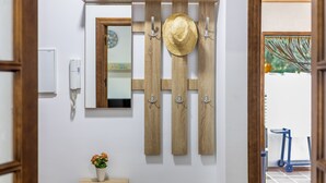 A hallway with a wooden wall-mounted rack holding a hat, a mirror, and a small potted plant. - Holiday Home "Brisa Marina" with Private Pool, Wi-Fi and Air Conditioning (Chiclana de la Frontera)