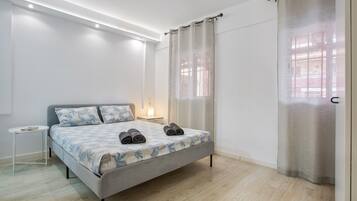 Een moderne slaapkamer met een bed, nachtkastje en een raam met gordijnen.