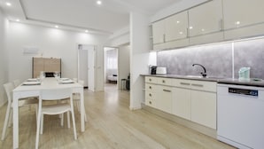 A modern kitchen with white cabinetry, a dining area with a table and chairs, and a built-in dishwasher. - Vacation Home 'Las Américas Seafront - Free Wi-fi' with Private Terrace, Wi-Fi and Air Conditioning (Playa de la Américas)