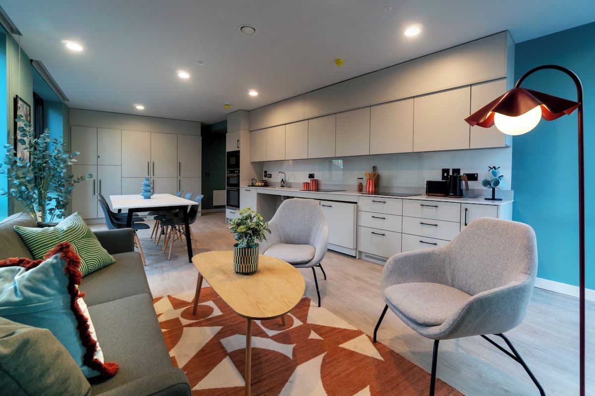 A modern living room with a sofa, chairs, a coffee table, and a dining area.