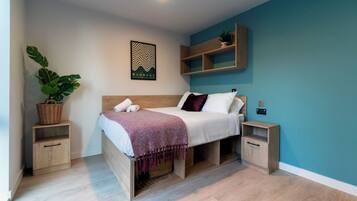 A modern bedroom with a wooden bed, a headboard, a wall-mounted shelf with a plant, and a framed poster.