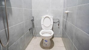 A bathroom with a white toilet, a handheld showerhead, and a wall-mounted faucet. - Residence fakir (Dakhla)