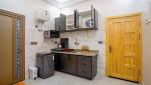A compact kitchen with a microwave, coffee machine, and a small trash bin. - Residence fakir (Dakhla)