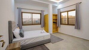 A modern bedroom with a bed, a wardrobe, and a window with curtains. - Residence fakir (Dakhla)