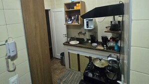 Een kleine keuken met basisvoorzieningen, zoals een magnetron, fornuis en spoelbak.