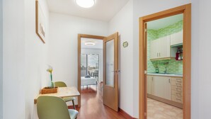 Un corridoio che conduce a una sala da pranzo con tavolo e sedie, una cucina con armadietti e una porta che dà su un'altra stanza.
