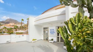 Un edificio con un cartello che riporta 'ISLAND VILLAGE HEIGHTS' e vista su un paesaggio montuoso sullo sfondo.