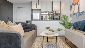 Una sala de estar moderna con un sofá gris, una mesa de centro y una planta grande.