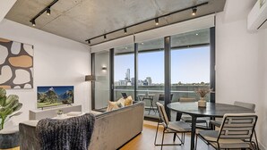 Una sala de estar moderna con un ventanal grande, un sofá, una mesa de comedor y un televisor.