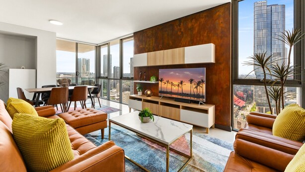 A modern living room with a large TV, leather sofas, a coffee table, and a city view. - Central 2-bed With Parking & Stunning Views (Sydney)