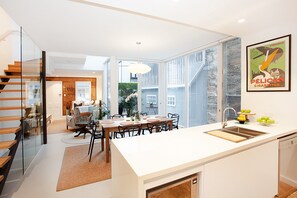 Une cuisine moderne avec un coin repas, un escalier et une vue sur l’extérieur.