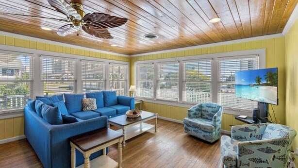 A living room with a blue sofa, a small table, a fish-patterned armchair, and a ceiling fan. - A Block Away- 5 BR/3BA- Dog Friendly- Pool (North Myrtle Beach)
