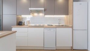 Una cocina moderna con armarios blancos, lavavajillas empotrado y un refrigerador de acero inoxidable.