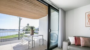 Un balcón con una mesa, sillas, un sofá y vistas a un cuerpo de agua.