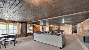Een ruime woonkamer met een hoge plafond, een bank, een eettafel en stoelen.