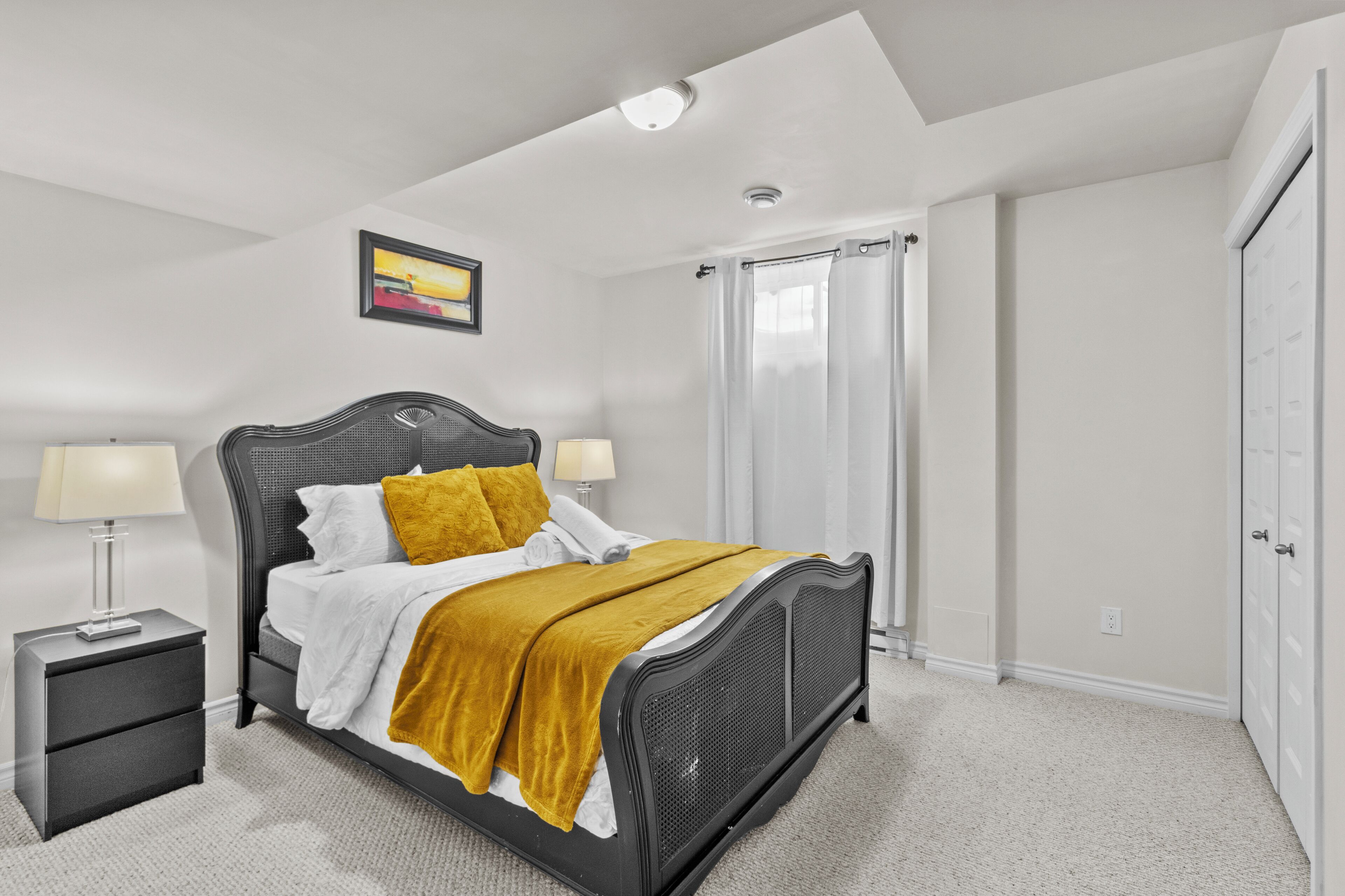 A bedroom with a bed, nightstand, and a window with curtains.