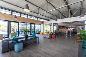 A spacious indoor area with a bar, seating, and large windows.