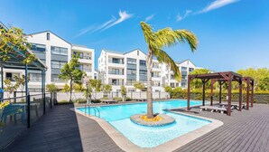 Une piscine dotée d’une terrasse en bois, entourée d’un bâtiment agrémenté de balcons.