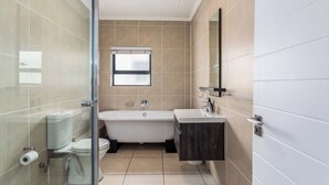 Une salle de bain moderne dotée d’une douche à parois de verre, d’une baignoire sur pieds et d’un meuble-lavabo avec miroir.